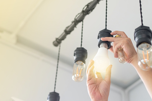 man changing compact-fluorescent (CFL) bulbs with new bulb.